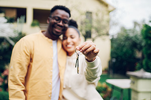 young couple hold the keys to the home they bought with an effective down payment